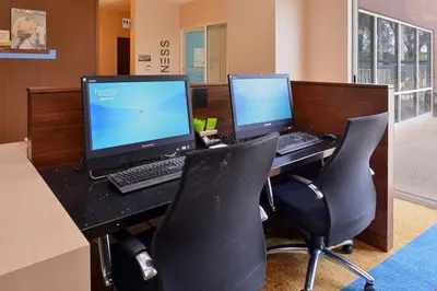 an office with two computers on a desk with chairs at Fairfield Inn Orlando Airport in Orlando