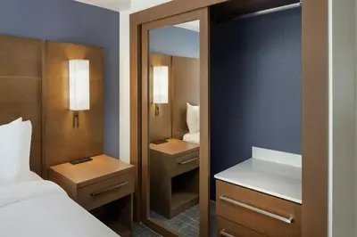 a small bedroom with a bed and a mirror at Residence Inn by Marriott Orlando East/UCF Area in Orlando