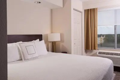 a bedroom with a white bed with a window at SpringHill Suites Orlando Airport in Orlando