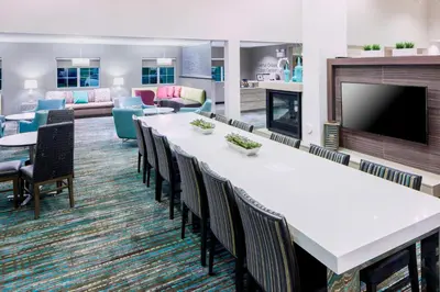 a large waiting room with tables and chairs and a fireplace at Residence Inn by Marriott Near Universal Orlando in Orlando