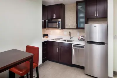 a kitchen with wooden cabinets and a stainless steel refrigerator at Residence Inn by Marriott Near Universal Orlando in Orlando