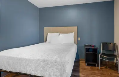 a bedroom with a bed and a blue wall at Extended Stay America Select Suites - Orlando - South in Orlando