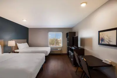 a hotel room with two beds and a desk and a window at WoodSpring Suites Orlando West - Clermont in Clermont