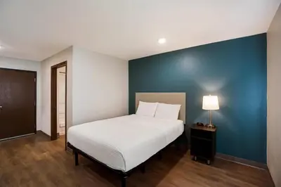 a bedroom with a bed and a blue wall at WoodSpring Suites Orlando West - Clermont in Clermont