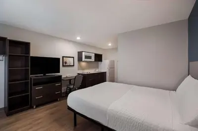 a bedroom with a bed and a desk with a computer at WoodSpring Suites Orlando West - Clermont in Clermont