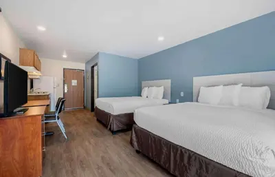 a hotel room with two beds and a flat screen tv at Extended Stay America Select Suites - Orlando - East in Orlando