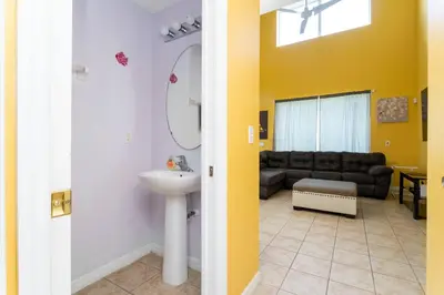 a bathroom with a sink and a living room with a couch at 7 Bedroom Mansion Near Disney in Kissimmee