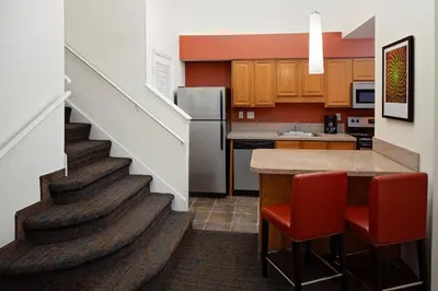 a kitchen with a staircase with red chairs and a counter at Residence Inn by Marriott Orlando Altamonte Springs Maitland in Orlando