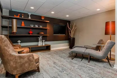 a living room with a tv and chairs and a table at Courtyard by Marriott Orlando Lake Mary North in Lake Mary