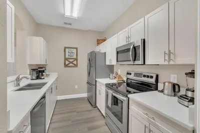 a kitchen with white cabinets and stainless steel appliances at Disney Bunk Room--Windsor Hills in Orlando