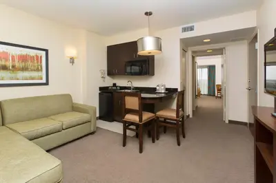 a living room with a couch and a table and a kitchen at Plaza Suites On International Drive Near Universal Epic in Orlando