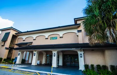 a building with a palm tree in front of it at Quality Inn & Suites By the Parks in Orlando