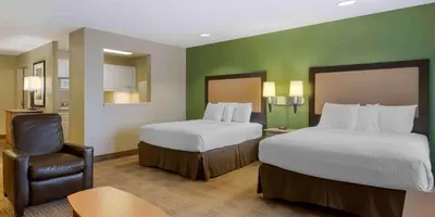 a hotel room with two beds and a chair at Extended Stay America Suites - Orlando - Orlando Theme Parks - Vineland Rd in Orlando