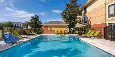 a swimming pool with chairs and a building at Extended Stay America Suites - Orlando - Orlando Theme Parks - Vineland Rd in Orlando