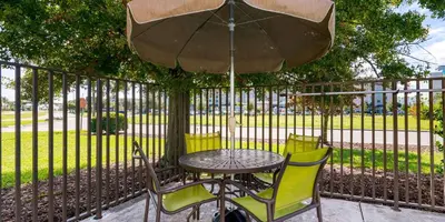 a table and chairs under an umbrella next to a fence at Extended Stay America Suites - Orlando - Orlando Theme Parks - Vineland Rd in Orlando