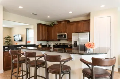 a kitchen with wooden cabinets and a island with bar stools at Wilmington Loop 6 Br Luxury Villa with Pool and Spa in Orlando