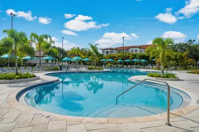 a swimming pool at a resort with blue umbrellas at Vero`s Gem Condo in Orlando