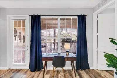 a desk in a room with a window with blue curtains at Vero`s Gem Condo in Orlando