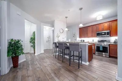 a kitchen with wooden cabinets and a kitchen island with bar stools at La Vista Lakeview Condo in Orlando