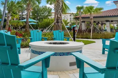 a patio with blue chairs and a fire pit at Miranda's Gem Condo in Orlando