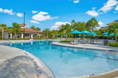 a swimming pool at a resort with blue umbrellas at Miranda's Gem Condo in Orlando