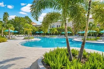 a resort swimming pool with palm trees and umbrellas at Spring Lakeview Condo in Orlando