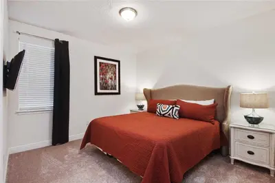 a bedroom with a bed with a red blanket and a window at DREAM HOUSE, ECOLAB Sanitzed NEAR DISNEY, POOL FENCE in Orlando