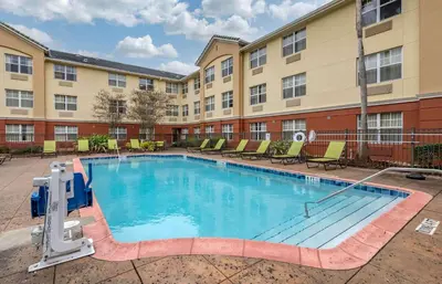 a pool in front of a building with chairs at Extended Stay America Suites - Orlando - Southpark - Commodity Circle in Orlando