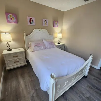 a bedroom with a white bed with pink pillows and two tables at Lake Berkley Home #213517 in Kissimmee