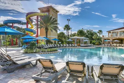 a pool at a resort with chairs and a roller coaster at Family Vacation Villa, Water Park, Endless Amenities in Kissimmee