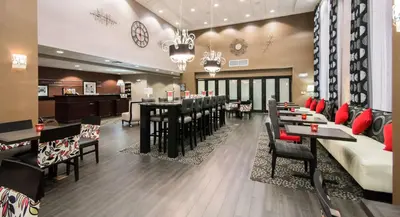 a restaurant with tables and chairs and a bar at Hampton Inn & Suites Orlando-John Young Parkway/South Park in Orlando