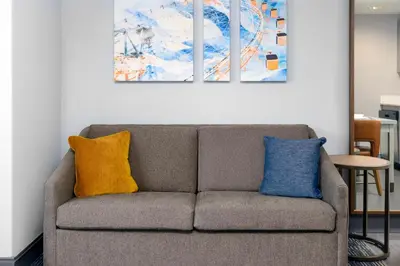 a couch in a living room with three paintings on the wall at Homewood Suites by Hilton Orlando-UCF Area in Orlando