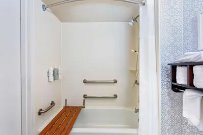 a bathroom with a bath tub with a wooden bench at Hampton Inn Orlando-International Airport in Orlando