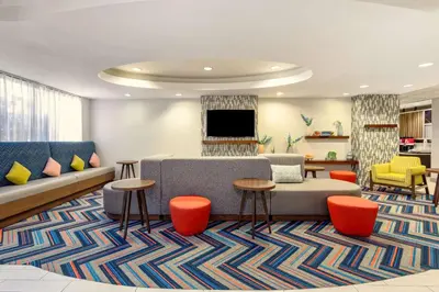 a living room with a couch and chairs and a tv at Hampton Inn Orlando-International Airport in Orlando