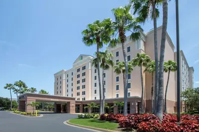 a rendering of the exterior of a hotel with palm trees at Embassy Suites by Hilton Orlando Airport in Orlando