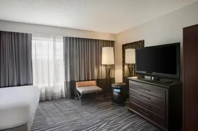 a hotel room with a bed and a flat screen tv at Embassy Suites by Hilton Orlando Airport in Orlando