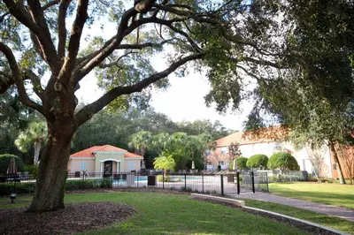 a tree in a park with a fence and a house at Four Bedrooms Resort TownHome 5128 in Kissimmee