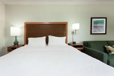 a hotel room with a bed and a green couch at Hampton Inn Orlando International Drive Convention Center in Orlando