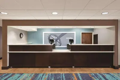 an office lobby with a waiting area with a smile sign on the wall at Hampton Inn Orlando International Drive Convention Center in Orlando
