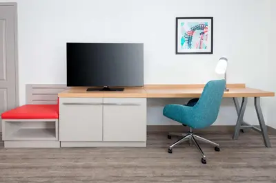a desk with a tv and a blue chair at Hilton Garden Inn Orlando International Drive North in Orlando