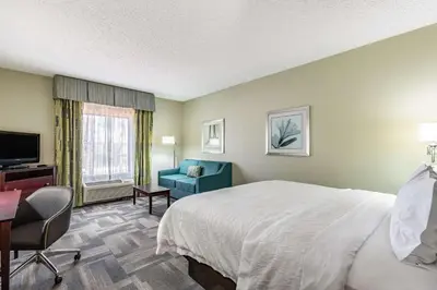 a hotel room with a bed and a chair and a television at Hampton Inn & Suites Orlando-South Lake Buena Vista in Kissimmee