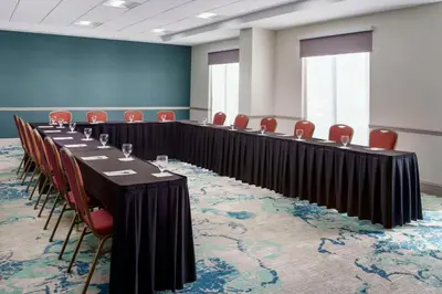 a conference room with a long table and red chairs at Hilton Garden Inn Orlando at SeaWorld in Orlando