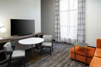 a living room with a tv and a table and chairs at Embassy Suites by Hilton Orlando North in Orlando