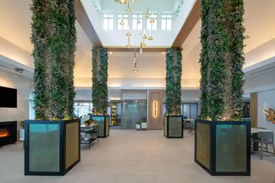 a lobby with tall columns with plants at Hilton Garden Inn Orlando Airport in Orlando