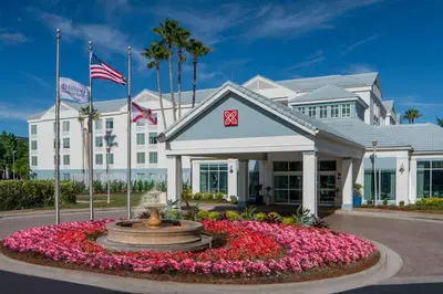 a hotel with flowers in front of a building at Hilton Garden Inn Orlando Airport in Orlando