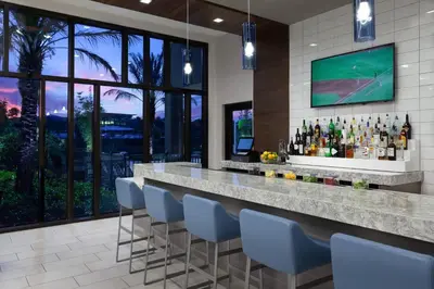 a bar with blue chairs and a television on the wall at SpringHill Suites by Marriott Orlando at Millenia in Orlando