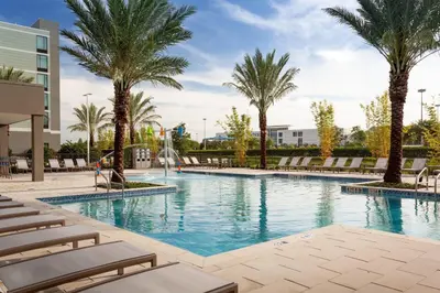 a swimming pool with palm trees and lounge chairs at SpringHill Suites by Marriott Orlando at Millenia in Orlando