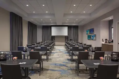 a conference room with tables and chairs and a projection screen at SpringHill Suites by Marriott Orlando at Millenia in Orlando