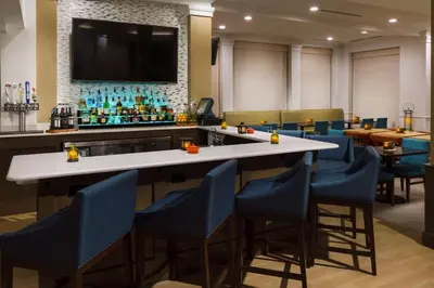 a bar in a restaurant with blue chairs at Hilton Garden Inn Lake Mary in Lake Mary