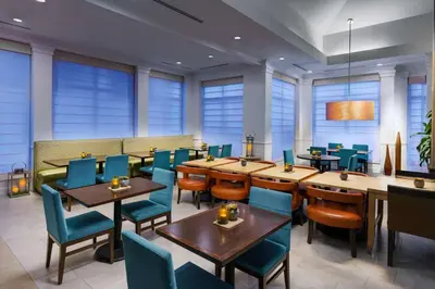 a restaurant with wooden tables and blue chairs at Hilton Garden Inn Lake Mary in Lake Mary